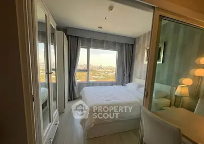 Modern bedroom with large window offering stunning city view, featuring elegant decor and ample natural light.
