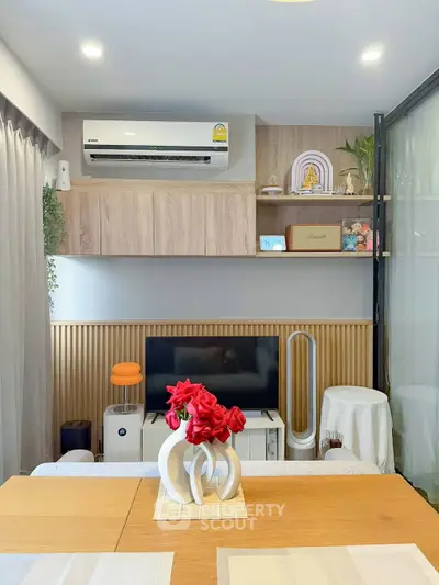 Modern living room with stylish decor and air conditioning, featuring a sleek TV setup and elegant shelving.