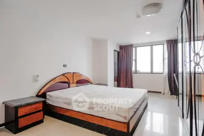 Spacious bedroom with modern furnishings and large window for natural light.