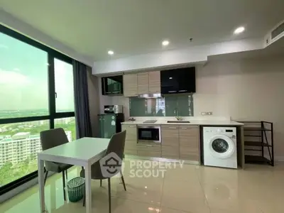 Modern kitchen with washing machine and dining area, featuring large windows with city view.
