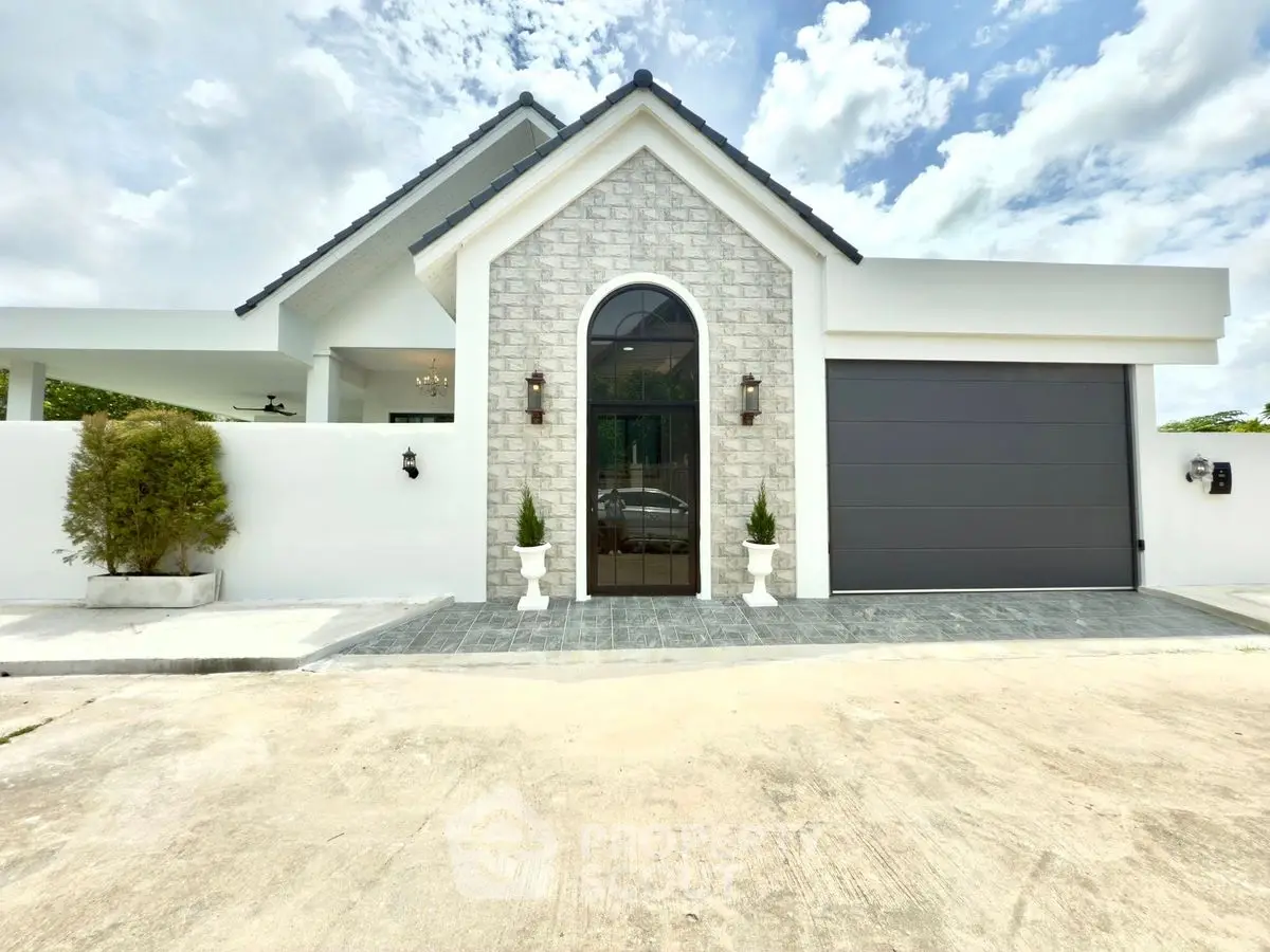 Charming modern house exterior with stone facade and sleek garage door under a bright sky.