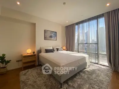 Spacious bedroom with large windows and city view, featuring modern decor and cozy ambiance.