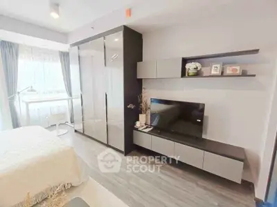 Modern bedroom with sleek furniture and natural light, featuring a stylish wardrobe and entertainment unit.
