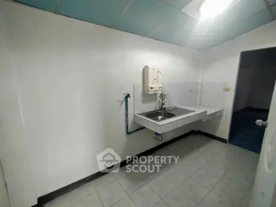 Minimalist kitchen with wall-mounted sink and tiled floor, ideal for compact spaces.