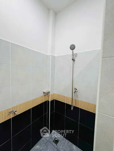 Modern bathroom shower area with sleek tile design and handheld showerhead.