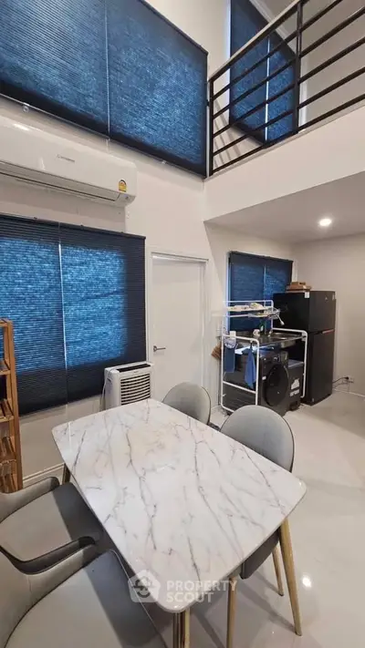 Modern dining area with marble table, stylish chairs, and loft view in a contemporary home.
