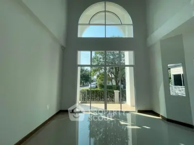 Spacious living room with high ceilings and large windows offering natural light and garden view.