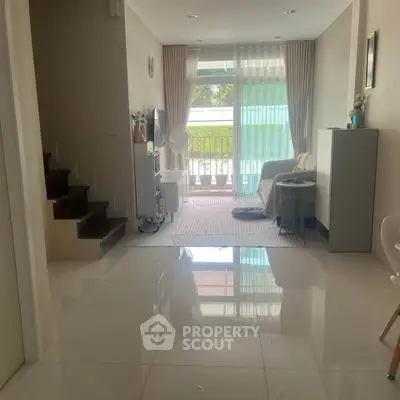 Charming living room with natural light and modern decor, featuring a cozy seating area and balcony access.