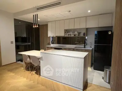 Modern kitchen with sleek design, featuring an island, dining area, and built-in appliances.