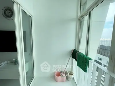 Modern balcony with glass doors and city view, featuring cleaning supplies.