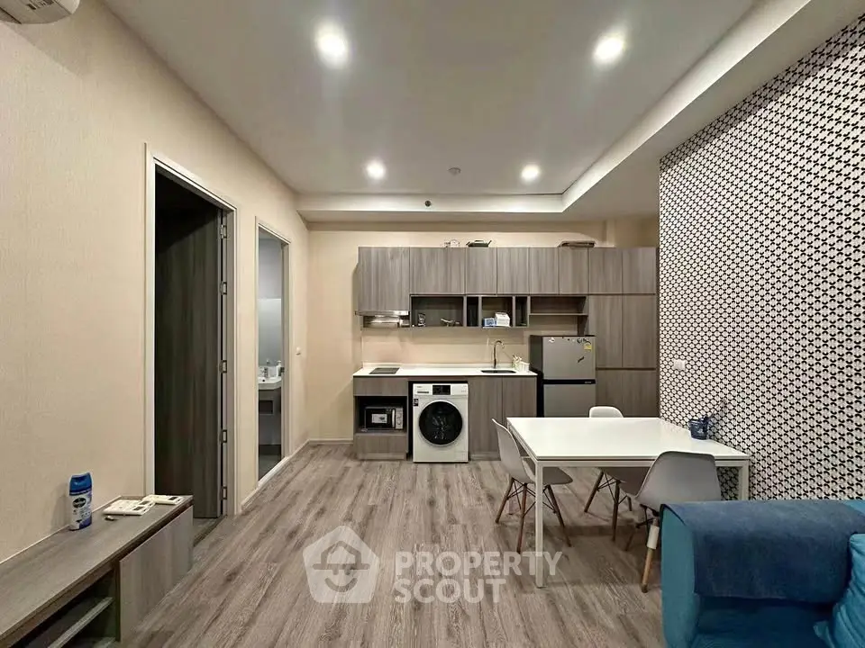 Modern open-plan living room with kitchen featuring sleek appliances and stylish decor.