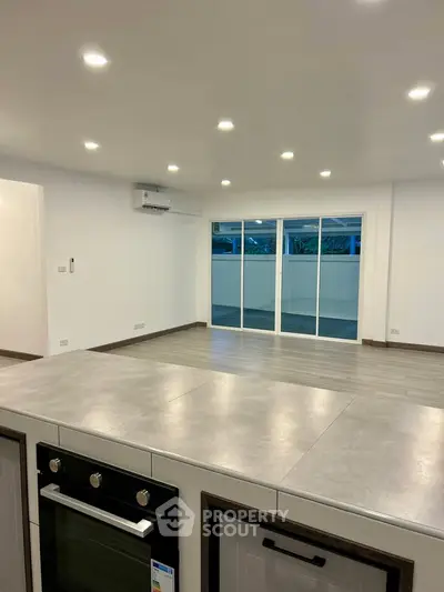 Spacious open-plan living area with modern kitchen and large windows.