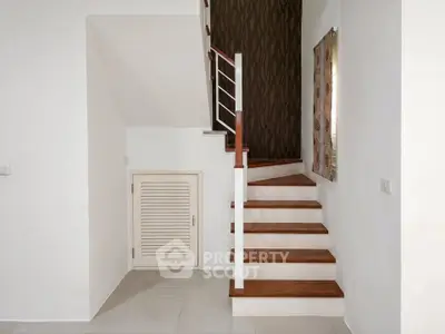 Modern staircase with wooden steps and white railing in a minimalist interior design