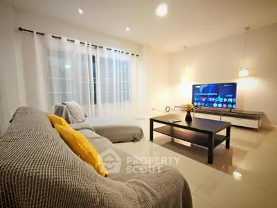 Spacious living room with modern decor and large TV, perfect for relaxation.