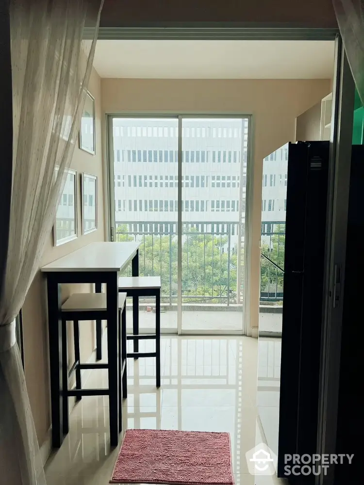 Modern apartment balcony with tall windows and sleek furniture overlooking cityscape.