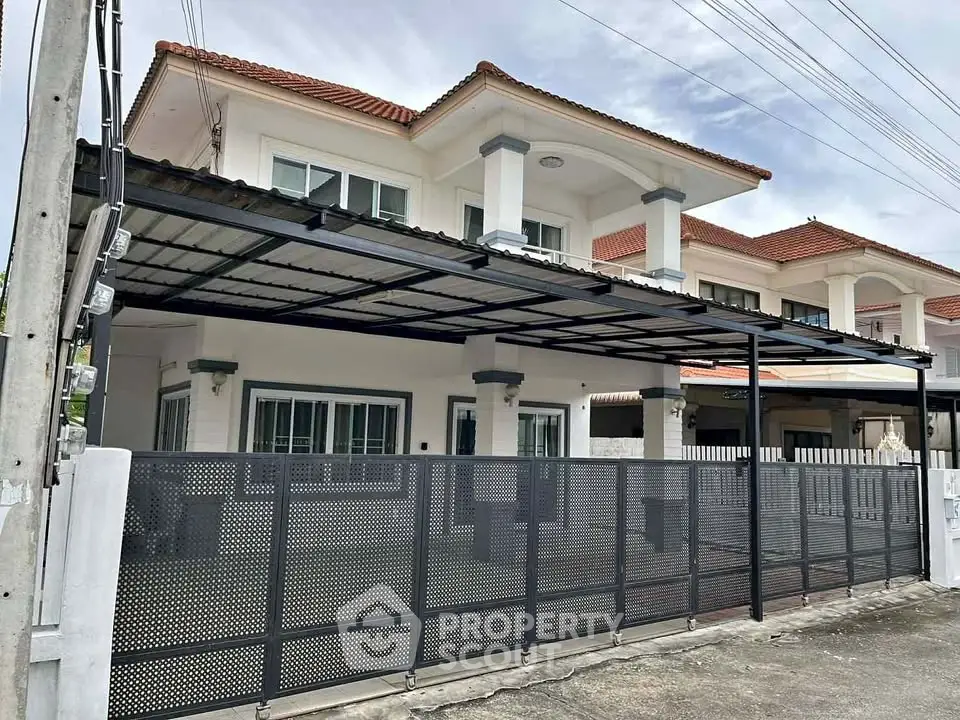 Charming two-story house with a modern gated entrance and spacious carport in a serene neighborhood.
