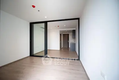 Spacious modern apartment with open layout and sleek design, featuring glass sliding doors and wood flooring.