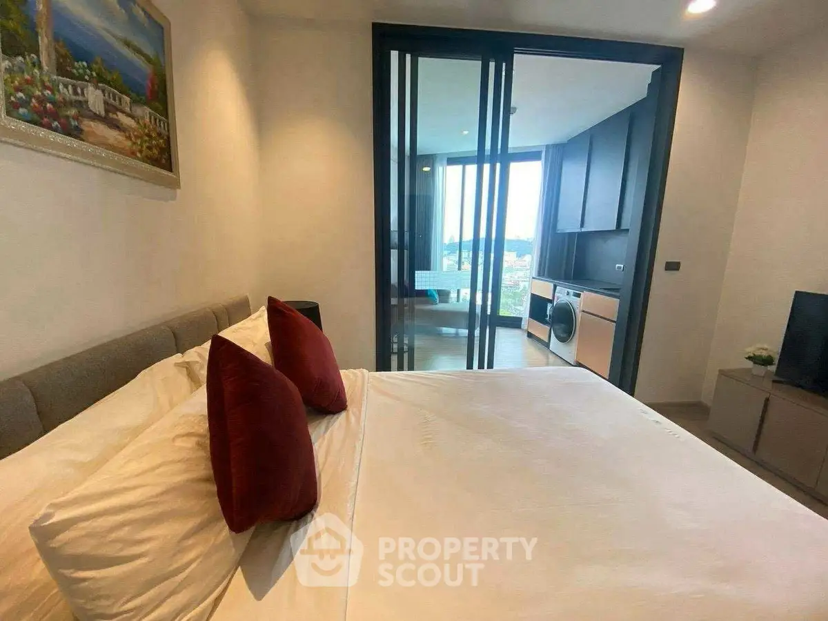 Modern bedroom with sliding glass doors leading to a bright living area and city view.