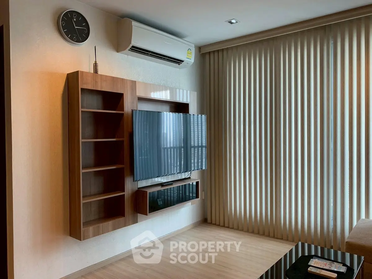 Modern living room with wall-mounted TV and sleek wooden shelves, featuring vertical blinds and air conditioning.