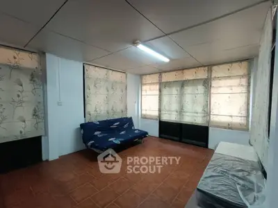 Spacious living room with tiled floor and floral curtains, featuring a cozy futon.
