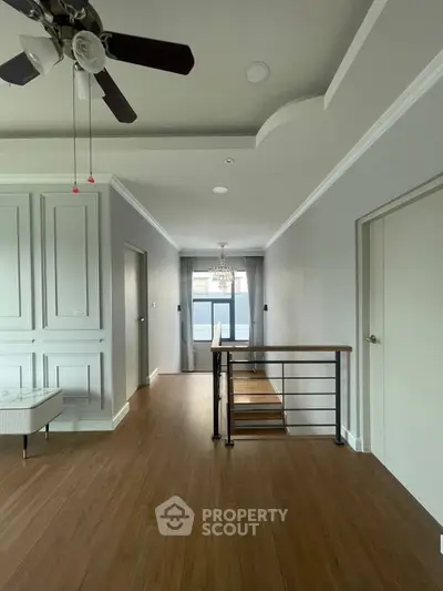 Spacious modern interior with elegant wood flooring and ceiling fan, perfect for stylish living.