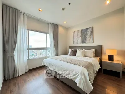 Spacious bedroom with elegant decor and large window offering city views
