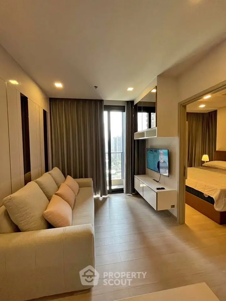 Modern living room with cozy sofa and TV, adjacent to a stylish bedroom with a city view.