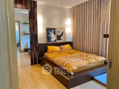 Modern bedroom with stylish decor and wooden flooring, featuring a cozy bed and elegant lighting.