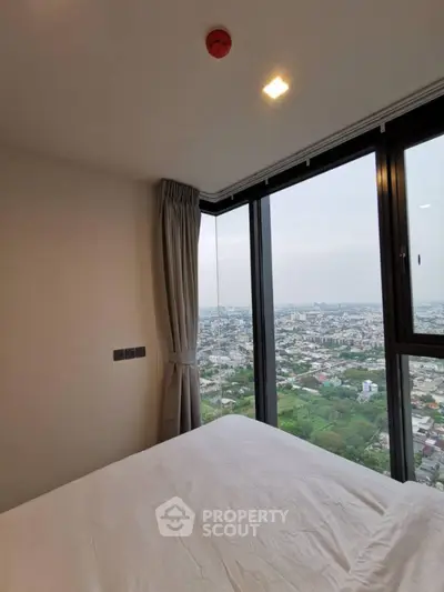 Stunning bedroom with panoramic city view from high-rise window.