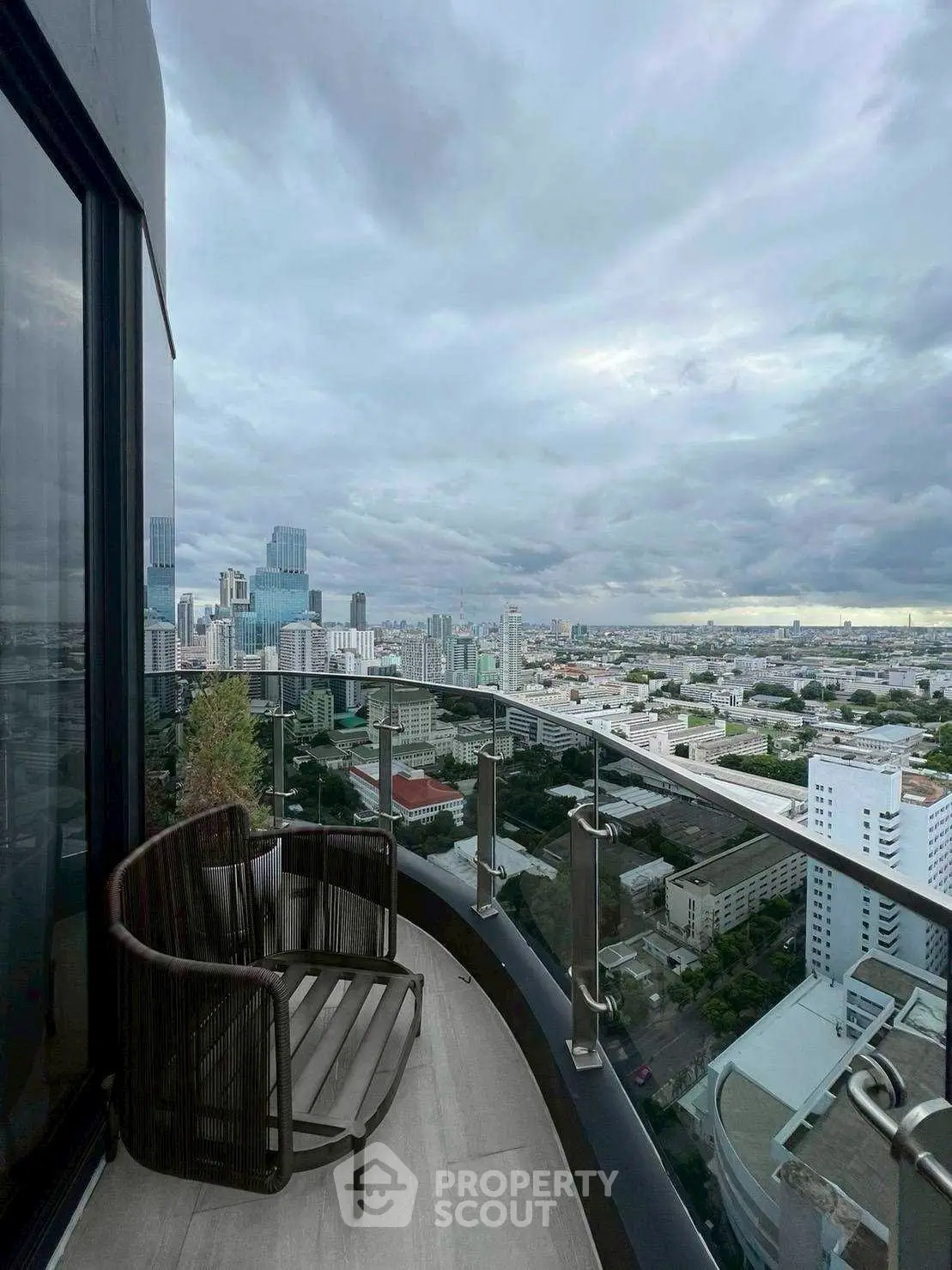 Stunning cityscape view from a modern high-rise balcony with sleek glass railing.