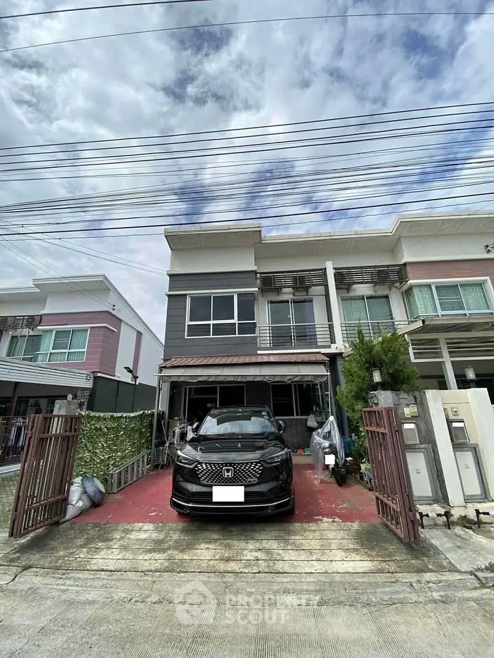 Modern townhouse with car parked in driveway, showcasing contemporary architecture and spacious exterior.
