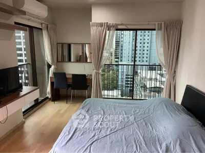 Modern bedroom with city view and natural light, featuring a cozy bed and workspace.