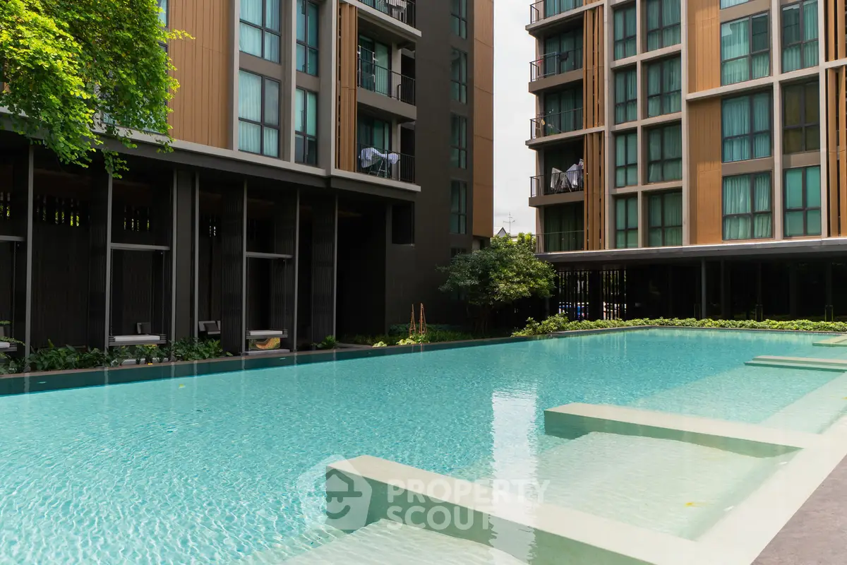 Luxurious modern apartment complex with a stunning outdoor pool and lush greenery.