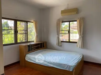 Spacious bedroom with large windows and natural light, featuring a comfortable bed and air conditioning.