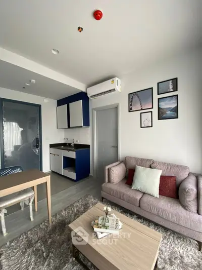 Modern living room with stylish decor and compact kitchen in open layout apartment.
