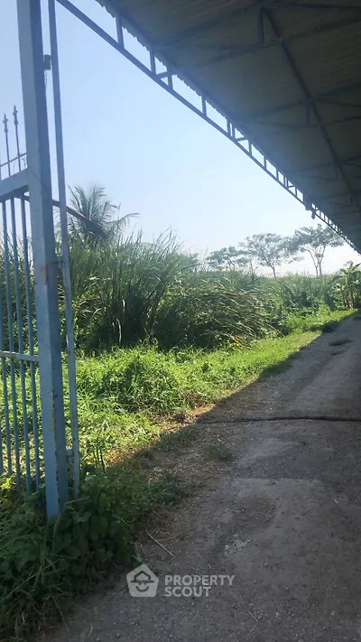 Expansive outdoor area with lush greenery and metal gate, ideal for development opportunities.
