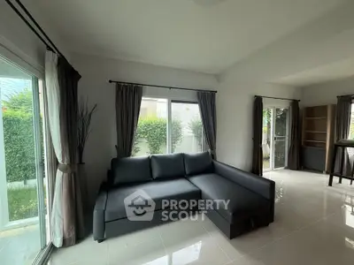 Spacious living room with modern sofa and large windows overlooking garden