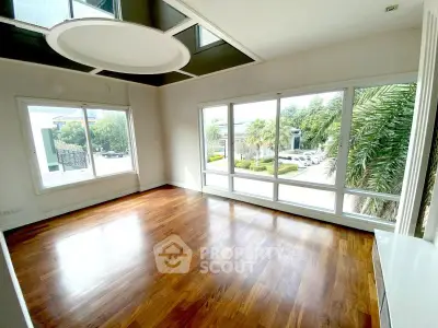 Spacious room with large windows and hardwood floors offering a bright and airy ambiance.