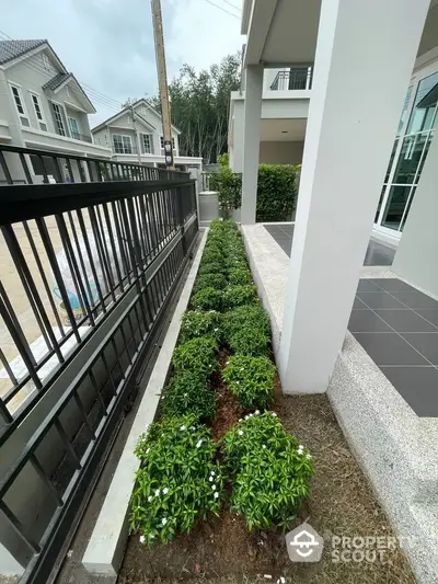 Modern residential entrance with landscaped garden and sleek gate design.