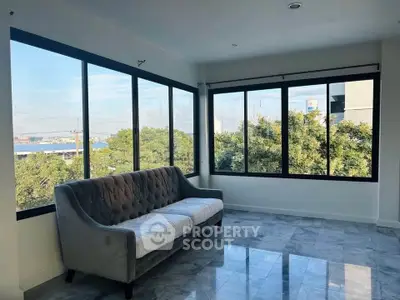 Spacious living room with large windows and scenic view, featuring a stylish gray sofa.
