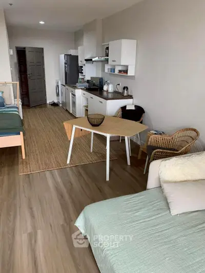 Modern studio apartment with open kitchen and cozy living area, featuring stylish decor and wooden flooring.