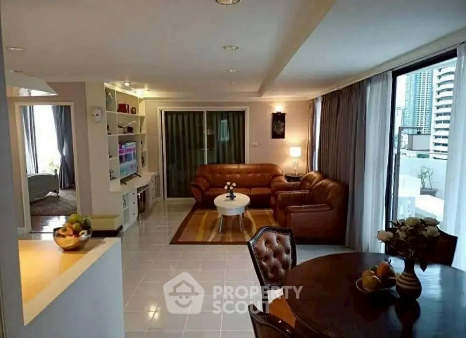 Spacious living room with leather sofas and city view balcony in modern apartment.