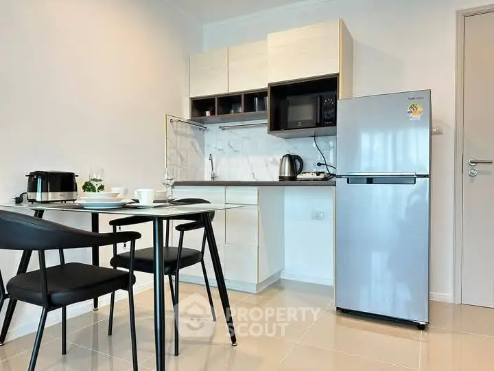 Modern kitchen with sleek appliances and dining area in stylish apartment.