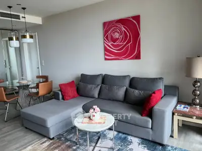 Modern living room with stylish gray sofa, red accents, and elegant dining area in open layout.