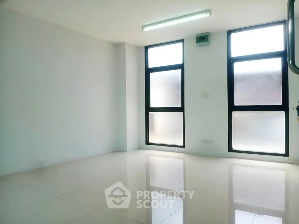 Spacious empty room with large windows and glossy tiled floor, perfect for customization.