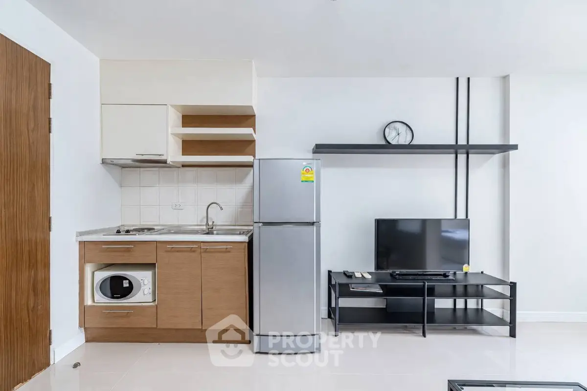 Modern compact kitchen with fridge and TV in stylish apartment
