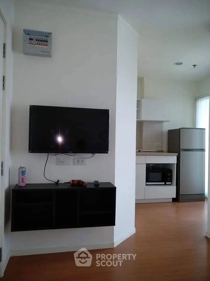 Modern apartment interior with wall-mounted TV and sleek kitchen appliances.