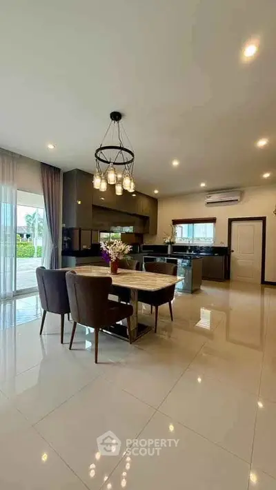 Spacious open-plan kitchen and dining area with modern lighting and large windows.