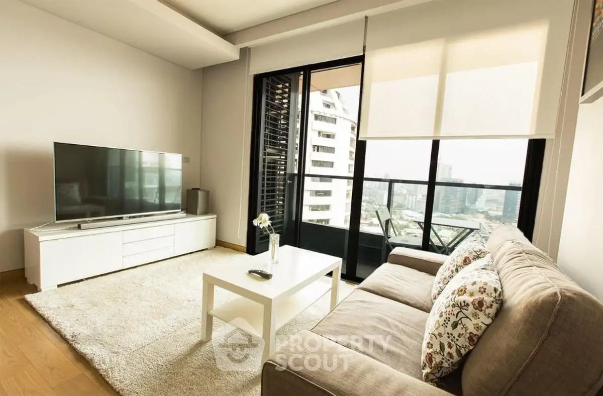 Modern living room with city view, featuring a cozy sofa, sleek TV setup, and access to a balcony.