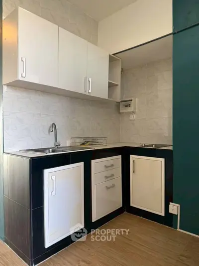 Modern compact kitchen with sleek cabinetry and dual sinks, perfect for efficient cooking in small spaces.